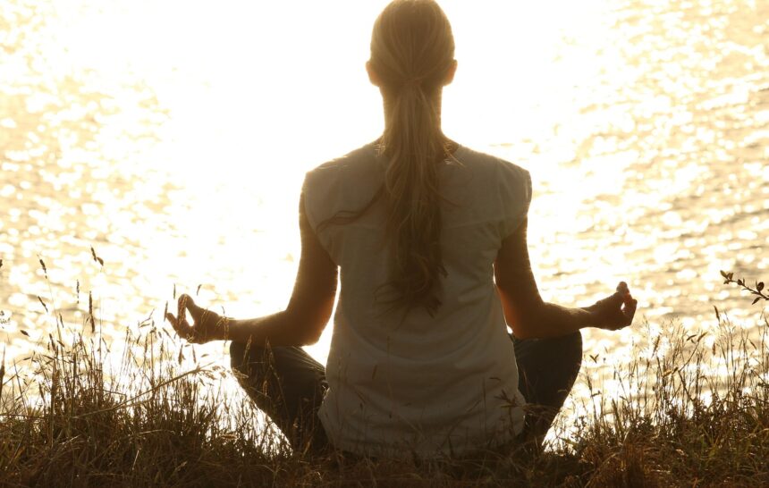 Woman meditating at sunset representing neurowellness and mind-body balance