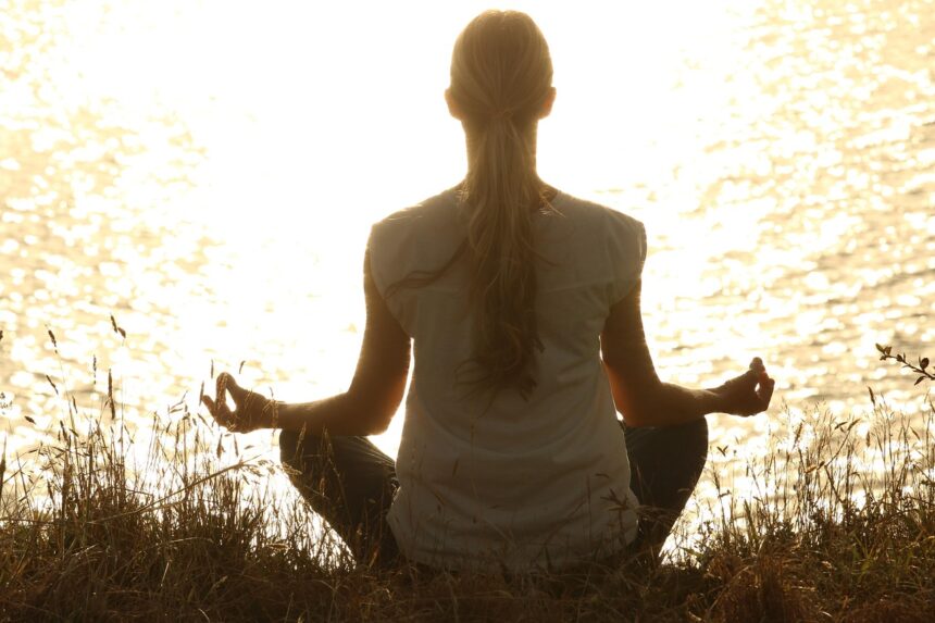Woman meditating at sunset representing neurowellness and mind-body balance